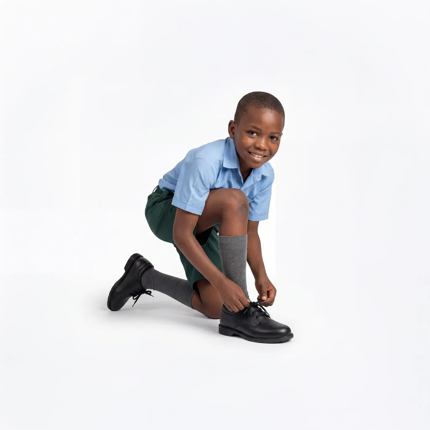 Concept image: a schoolboy kneeling to tie black school shoes.