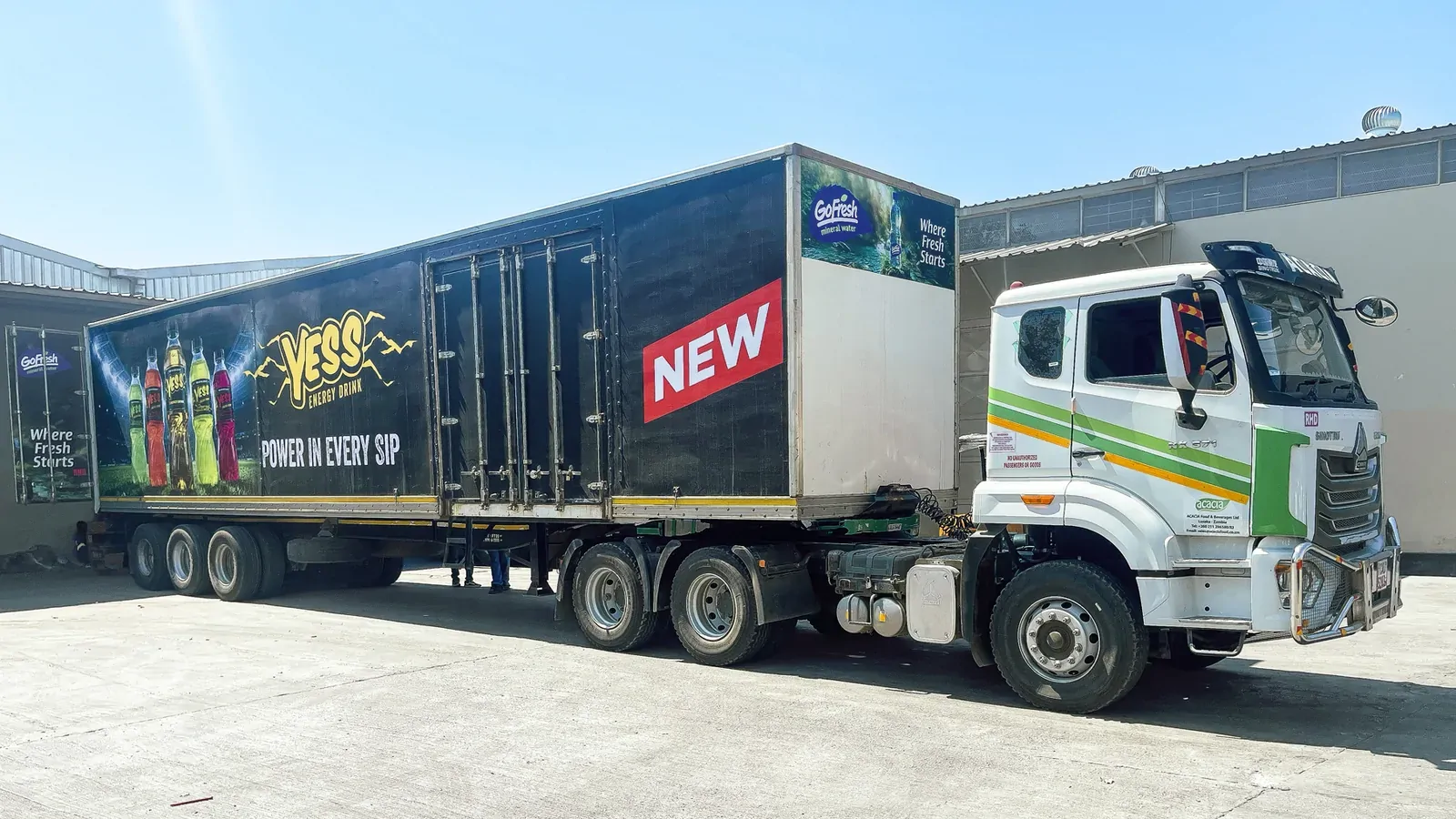 Truck and trailer wrapped in YESS livery, parked in a yard.