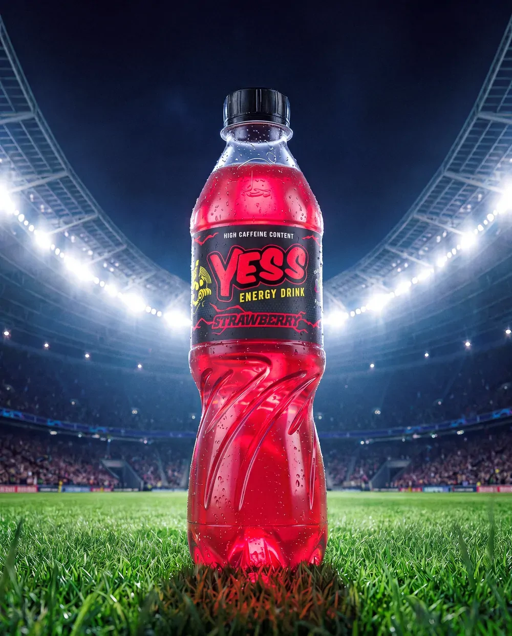 A YESS Strawberry bottle on a floodlit stadium pitch.